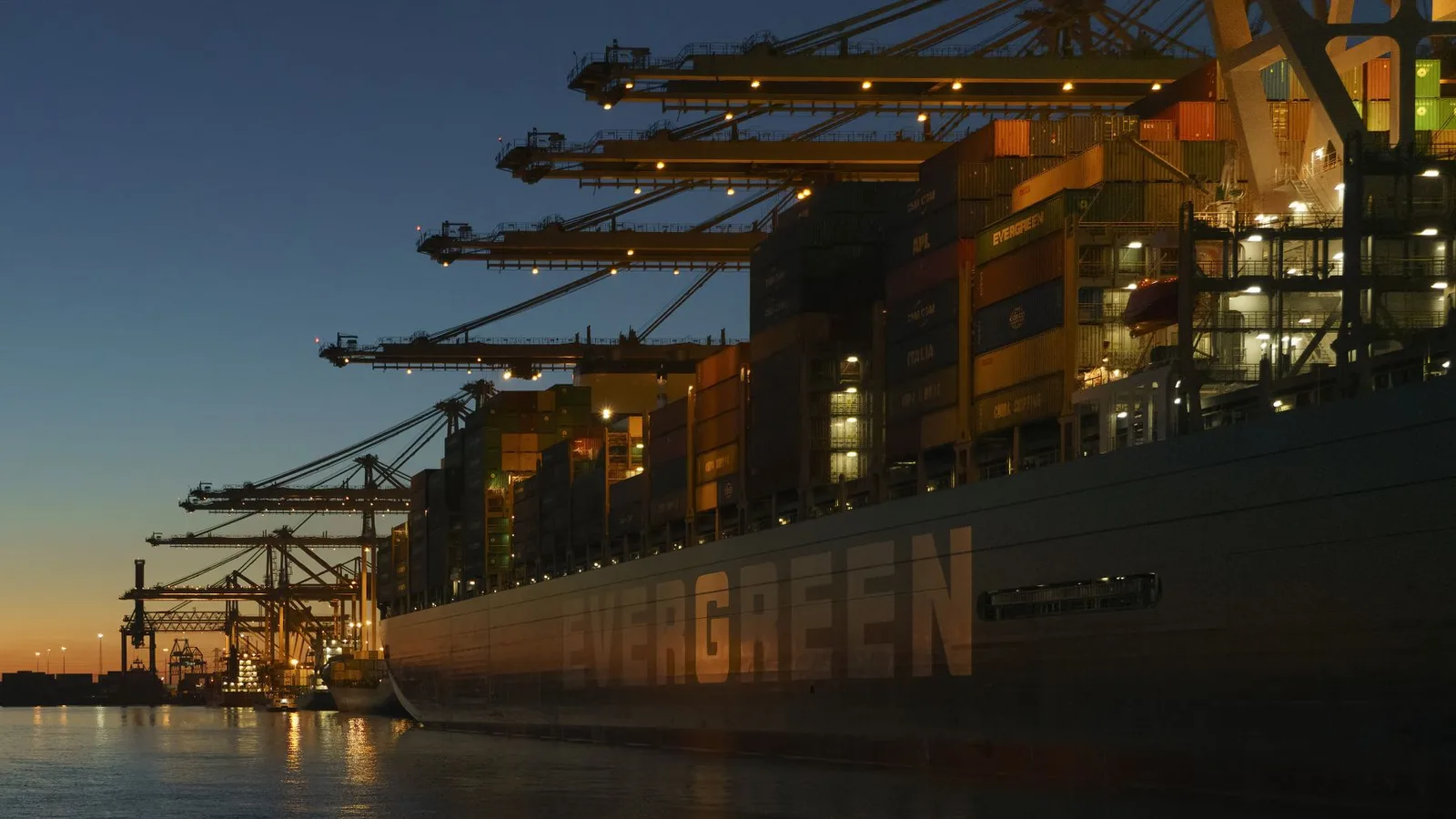 Container ship and port cranes at twilight
